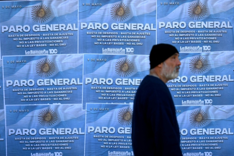 Un homme passe devant des affiches appelant à la grève générale le 9 mai 2024 à Buenos Aires, la deuxième depuis le début du mandat du président argentin Javier Milei ( AFP / Luis ROBAYO )