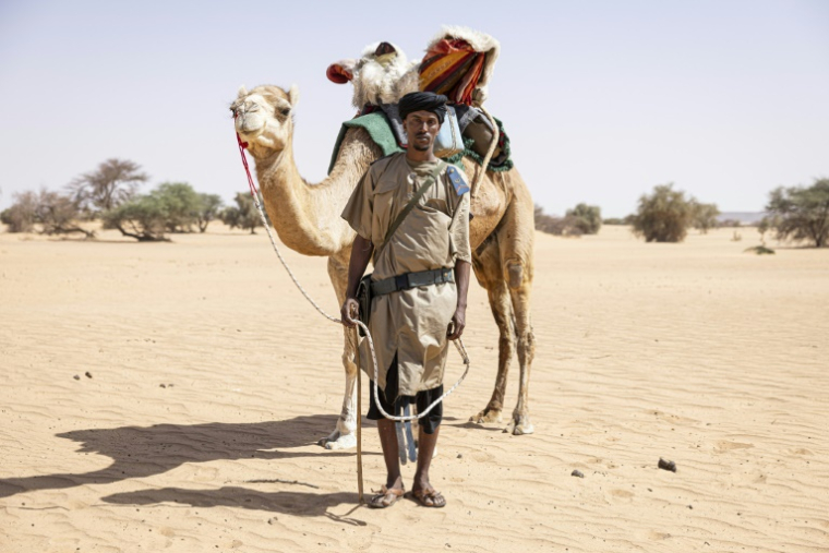 Sidnq, un membre de l'unité du Groupement nomade de la Garde nationale mauritanienne, pose pour un portrait à côté de son dromadaire dans la région de Hodh Ech Chargui (Mauritanie), le 7 avril 2025 ( AFP / PATRICK MEINHARDT )
