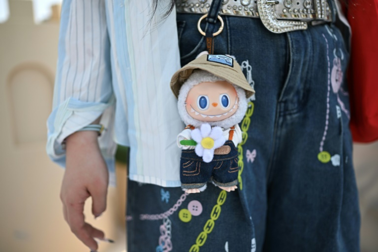 Une visiteuse porte à sa ceinture une figurine Labubu au parc à thème Pop Land de Pop Mart à Pékin, le 18 juin 2025 ( AFP / Pedro PARDO )