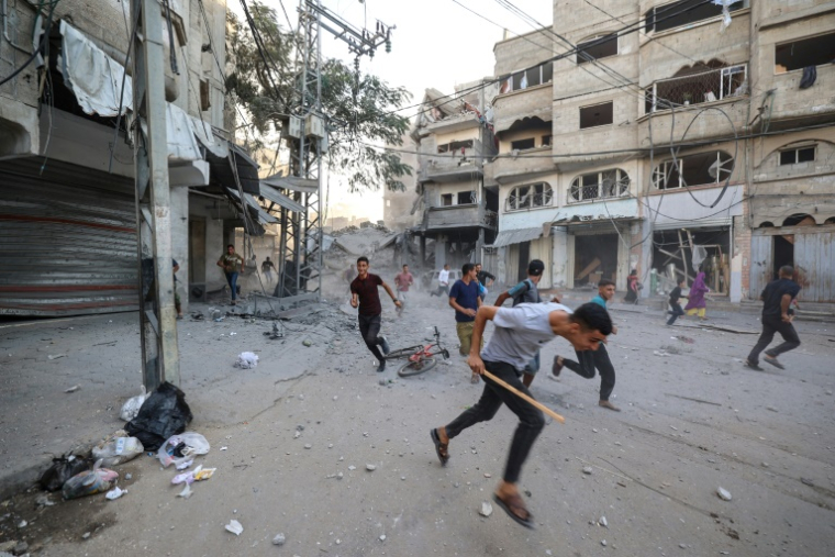 Des Palestiniens courent pour se mettre à l'abri après une frappe israélienne à Bureij, dans le centre de la bande de Gaza, le 19 octobre 2025 ( AFP / Eyad BABA )