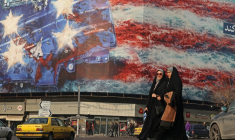 Des Iraniennes marchent devant un panneau anti-américain installé sur la place Enghelab à Téhéran, le 26 janvier 2026 ( AFP / ATTA KENARE )