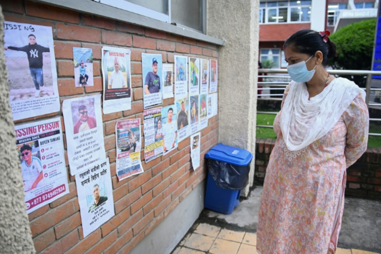 Une femme regarde les photos de personnes portées disparues dans la crue destructrice qui a fait plus de 600 morts à la frontière entre le Népal et la Chine, le 29 août 2026 à Katmandou ( AFP / PRAKASH MATHEMA )