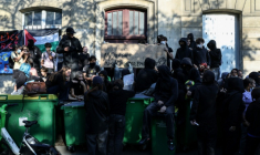 Des manifestants se tiennent debout sur des poubelles empilées à l'entrée du lycée Arago à Paris, le 29 septembre 2026 ( AFP / Kenzo TRIBOUILLARD )