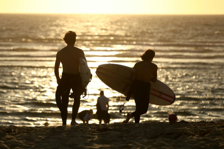 Des surfeurs sur la plage du Porge (Gironde), où quelque 220 personnes se sont retrouvées le 7 août 2026  pour une soirée de solidarité après le mégafeu qui ravagé la commune ( AFP / ROMAIN PERROCHEAU )