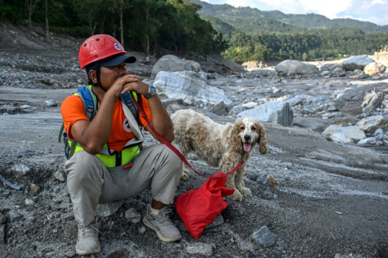 Un secouriste avec un chien de sauvetage sur les rives de la rivière Trishuli dans le district de Nuwakot, au Népal, où ils recherchent des disparus le 30 septembre 2026 ( AFP / Prakash MATHEMA )