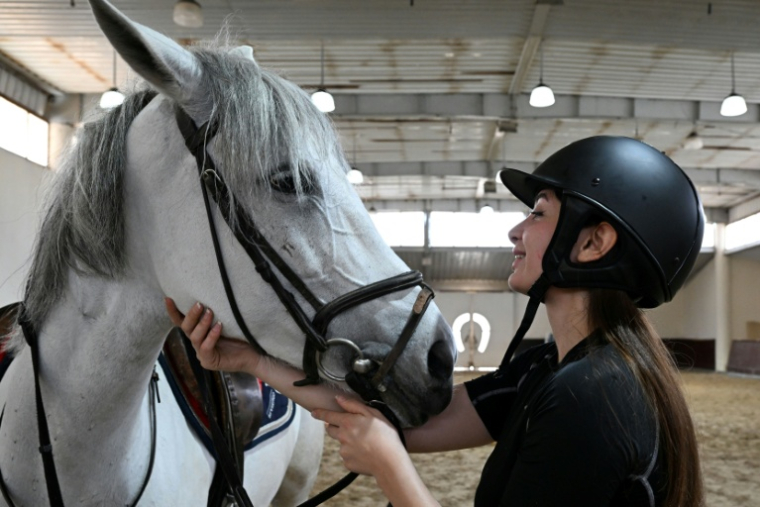 Une cavalière flatte son cheval avant de participer à une compétition équestre à Dimas, au nord-ouest de Damas, le 9 mai 2025. ( AFP / LOUAI BESHARA )