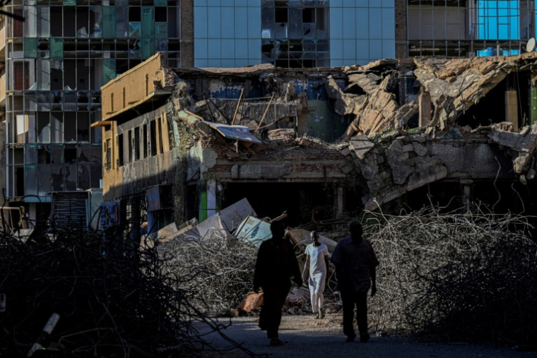 Des hommes marchent devant un bâtiment détruit à Khartoum, le 16 avril 2026 ( AFP / Khaled DESOUKI )