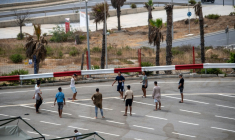 Des migrants jouent au foot sur un parking près d'abris temporaires installés pour eux, le 27 août 2026 à Ceuta ( AFP / Antonio Sempere )