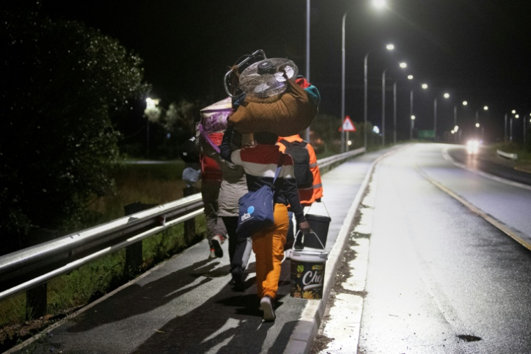 Des étrangers portant leurs affaires marchent dans une rue de Stanford, à environ 120 km du Cap (Afrique du Sud), le 2 juin 2026, après avoir été menacés par des groupes anti-migrants. ( AFP / RODGER BOSCH )