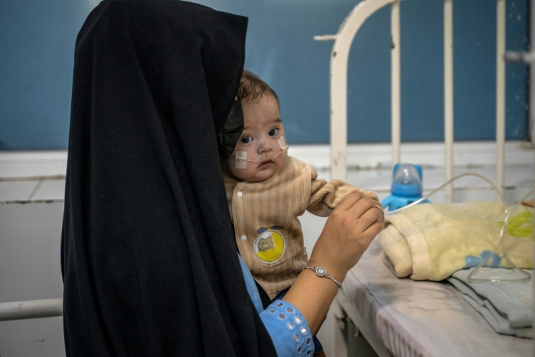 Une femme afghane, Najiba, tient son enfant, Artiya, qui souffre d’une malformation cardiaque congénitale, à l’intérieur du centre de nutrition thérapeutique de Médecins Sans Frontières (MSF) dans un hôpital à Hérat le 8 janvier 2025 ( AFP / Wakil KOHSAR )