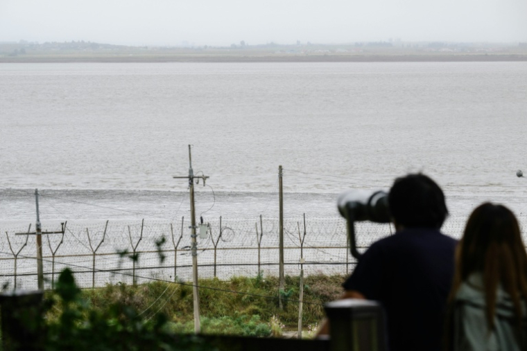 Sur cette photo prise le 7 octobre 2025, des personnes observent la côte nord-coréenne depuis l'île de Gyodong, pendant la fête familiale d'automne de Chuseok ( AFP / ANTHONY WALLACE )