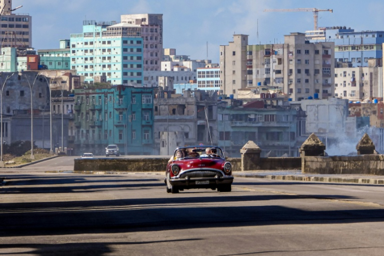 Des touristes circulent dans une vieille voiture américaine utilisée comme taxi sur le Malecon, l'avenue de bord de mer de La Havane, peu fréquentée en raison d'une pénurie de combustible, le 8 février 2026 ( AFP / ADALBERTO ROQUE )