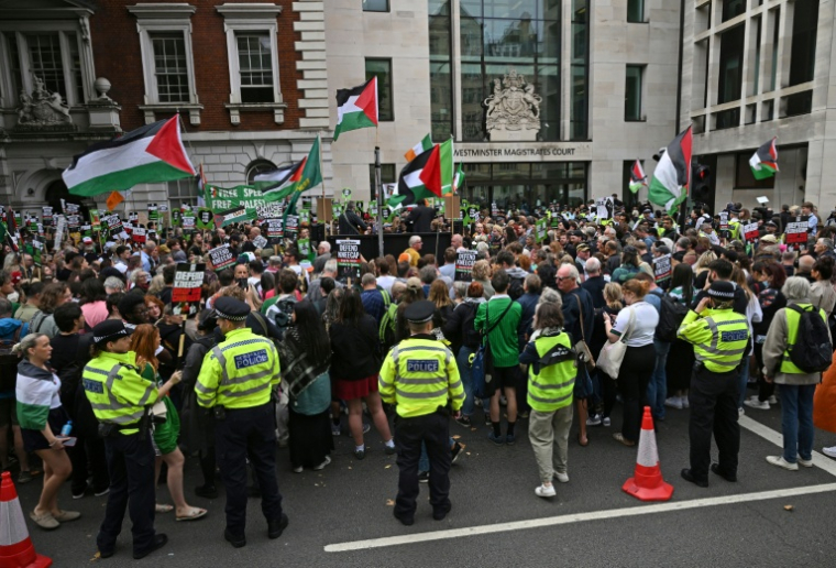 Des policiers encadrent une manifestation de soutien au trio nord-irlandais Kneecap, et à son chanteur Liam O'Hanna alias Mo Chara, où des drapeaux palestiniens sont agités, à Londres le 20 août 2025 ( AFP / JUSTIN TALLIS )