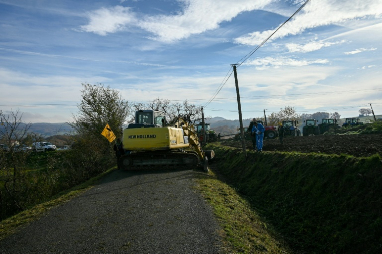 Un agriculteur, à l'aide d'un tracteur, bloque la route avec des troncs d'arbres lors d'une manifestation pour empêcher l'abattage d'un troupeau de 200 vaches, suite à la détection de la dermatose nodulaire contagieuse (DNC) aux Bordes-sur-Arize, le 11 décembre 2025 en Ariège ( AFP / Matthieu RONDEL )