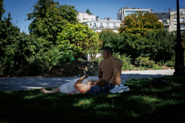 Des personnes sont allongées sur l'herbe à l'ombre place de la Nation, à Paris, le 28 juillet 2026, lors de la quatrième vague de chaleur en France ( AFP / Simon WOHLFAHRT )