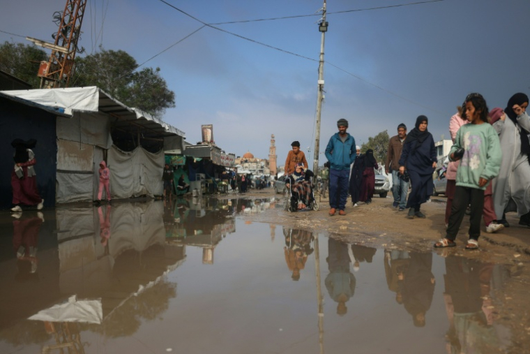 Des Palestiniens déplacés dans une rue inondée après de fortes pluies à Khan Younès, dans le sud de la bande de Gaza, le 24 février 2026 ( AFP / Bashar Taleb )