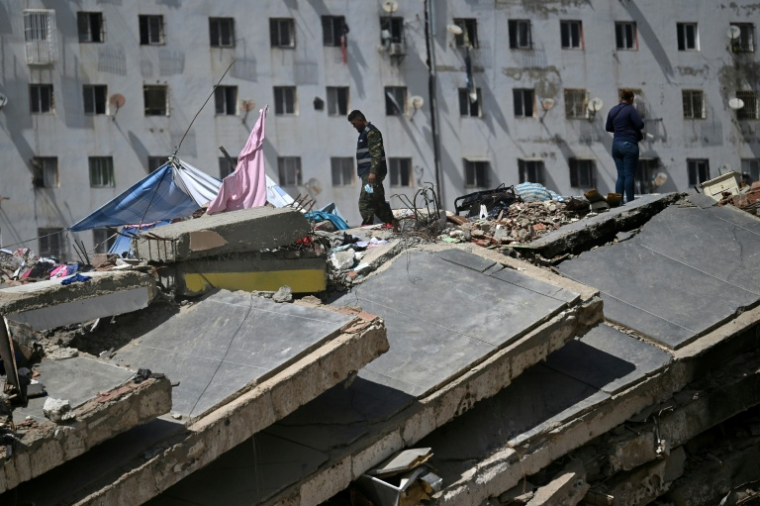 Deux personnes se tiennent au sommet des décombres d'un bâtiment détruit par les séismes du 24 juin à Caraballeda, au Venezuela, le 17 juillet 2026  ( AFP / Raul ARBOLEDA )