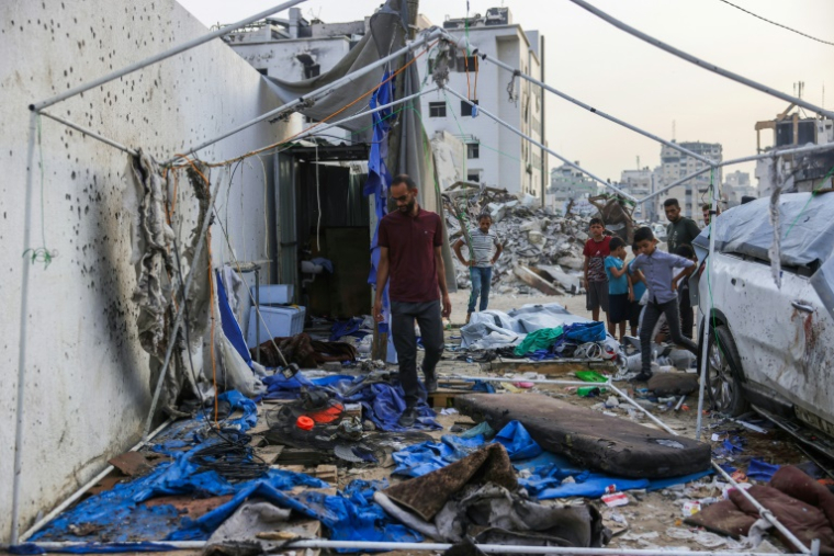 Des personnes regardent les restes de la tente utilisée par les journalistes d'Al Jazeera à Gaza-ville, devant l'hôpital al-Chifa, après une frappe israélienne, le 11 août 2025 ( AFP / BASHAR TALEB )