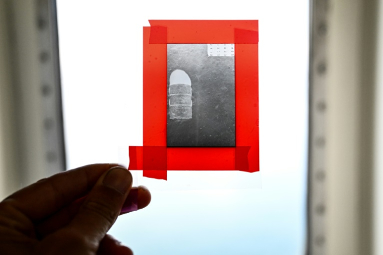 Un chercheur du CNRS montre le négatif d'un baril de déchets nucléaires photographié en 1985, à bord du navire scientifique Atalante avant son départ du port de Brest pour une mission scientifique, le 15 juin 2025 dans le Finistère ( AFP / Sebastien Salom-Gomis )