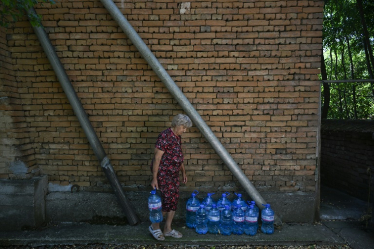 Rumyana Tsoneva porte des bouteilles d'eau dans le village de Gorna Studena, le 2 juillet 2025 en Bulgarie ( AFP / Nikolay DOYCHINOV )