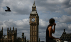 Une femme est assise sur la rive sud de la Tamise, avec vue sur "Big Ben" et le palais de Westminster, dans le centre de Londres, à la veille de l'arrivée au pouvoir d'Andy Burnham en tant que Premier ministre britannique, le 19 juillet 2026 ( AFP / Henry Nicholls )