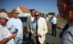 Nigel Farage, (c) chef du parti britannique Reform UK, parle avec des électeurs à la sortie d'un bureau de vote installé dans une école primaire de Walton-on-the-Naze, dans l'Essex, lors de l'élection partielle de Clacton, le 13 août 2026 ( AFP / Henry NICHOLLS )