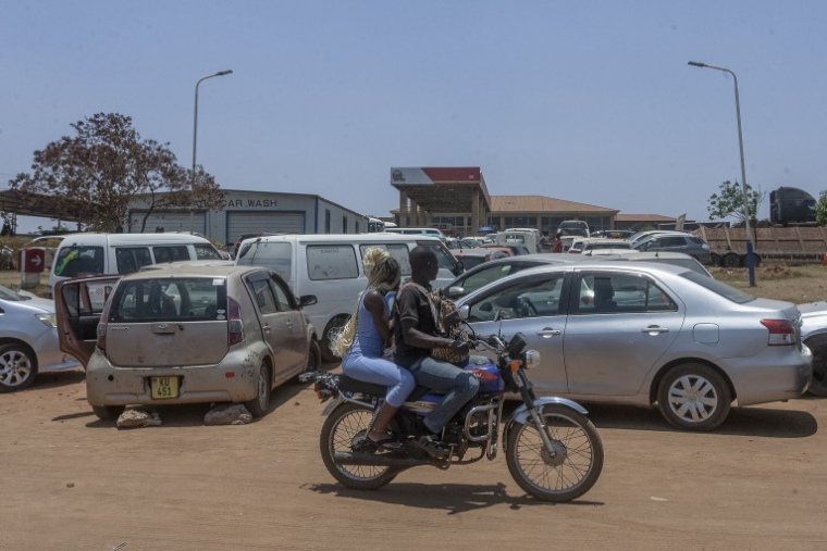 Des motocyclistes passent devant des véhicules faisant la queue pour du carburant à la station-service Best Oil, dans la zone 49 à Lilongwe, la capitale du Malawi, le 22 octobre 2026 ( AFP / Amos GUMULIRA )