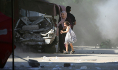 Une Palestinienne et sa fille se précipitent pour se mettre à l'abri lors d'une frappe israélienne dans le camp d'Al-Bureij, dans le centre de la bande de Gaza, le 4 juillet 2025 ( AFP / Eyad BABA )