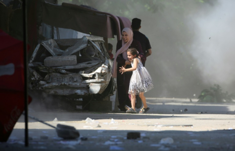 Une Palestinienne et sa fille se précipitent pour se mettre à l'abri lors d'une frappe israélienne dans le camp d'Al-Bureij, dans le centre de la bande de Gaza, le 4 juillet 2025 ( AFP / Eyad BABA )