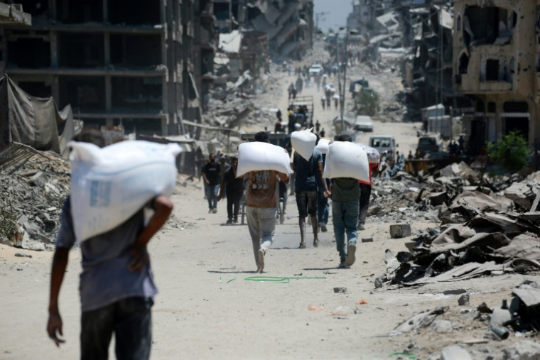 Des Palestiniens portent des sacs de farine à Jabalia, dans le nord de la bande de Gaza, le 1er août 2025 ( AFP / Bashar TALEB )