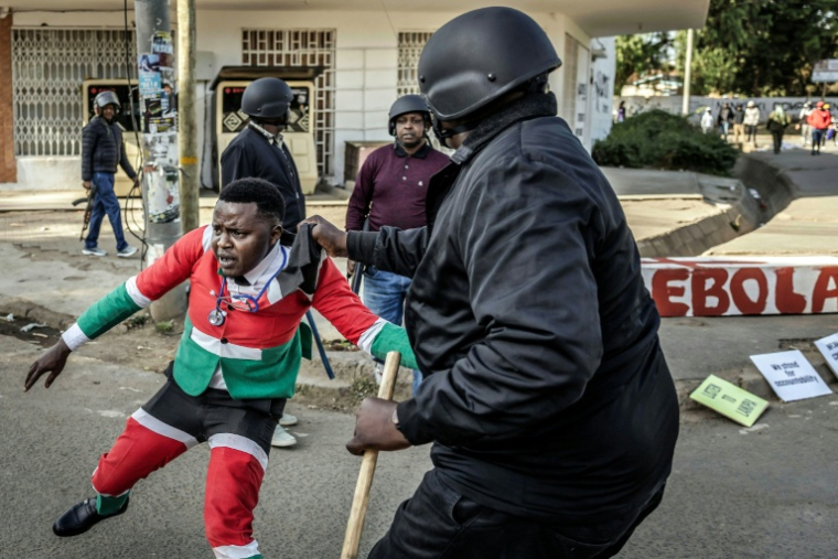 Un manifestant arrêté par un policier lors d'une manifestation contre un centre de quarantaine Ebola construit par les États-Unis sur la base aérienne de Laikipia, le 9 juin 2026 à Nanyuki, au Kenya ( AFP / Luis TATO )