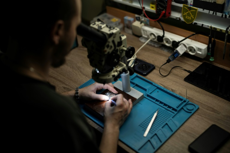 Un soldat ukrainien du bataillon de drones du 225e régiment d'assaut séparé soude un microprocesseur dans un atelier tenu secret, le 12 juin 2025 ( AFP / Florent VERGNES )