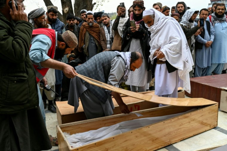 Abdul Hai Hamidi (c) regarde dans un cercueil à la recherche d'un proche lors des deuxièmes funérailles collectives des victimes tuées par une frappe aérienne pakistanaise sur un hôpital pour toxicomanes, à la mosquée Eid Gah de Kaboul le 26 mars 2026 en Afghanistan ( AFP / Wakil KOHSAR )