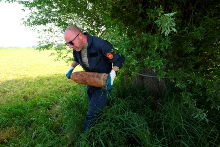 Un membre de l'équipe de déminage de la DOVO ramasse de vieux obus de la Première Guerre mondiale trouvés dans la campagne du nord-ouest de la Belgique, près d'Ypres, le 19 mai 2025 ( AFP / Nicolas TUCAT )