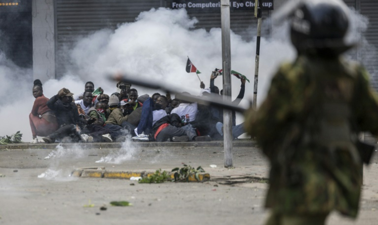 Des manifestants se mettent à couvert alors que la police tire des gaz lacrymogènes, le 25 juin 2025 à Nairobi, au Kenya ( AFP / SIMON MAINA )