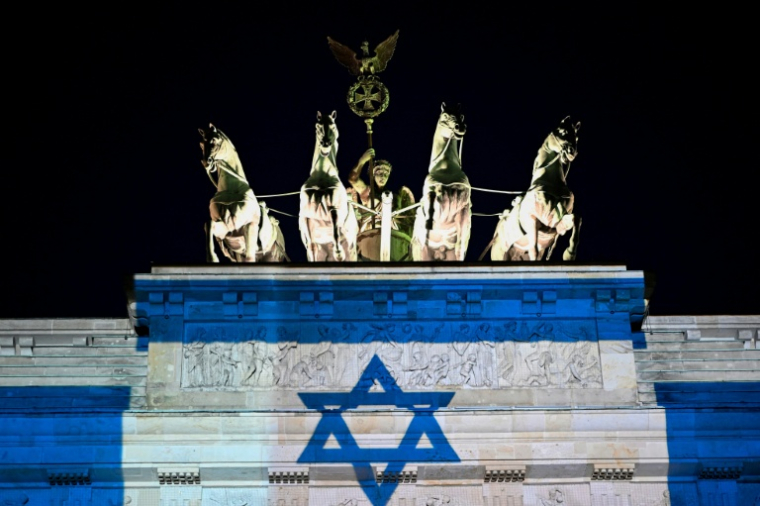 La porte de Brandebourg illuminée aux couleurs du drapeau israélien, le 7 octobre 2026 à Berlin, à l'occasion du troisième anniversaire de l'attaque du Hamas contre Israël ( AFP / Tobias SCHWARZ )