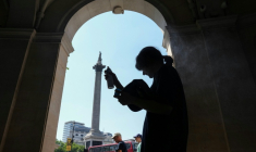 Une femme se protège de la chaleur du soleil, dans l'ombre d'une entrée sur Trafalgar Square, à Londres, le 8 juillet 2026 ( AFP / CARLOS JASSO )