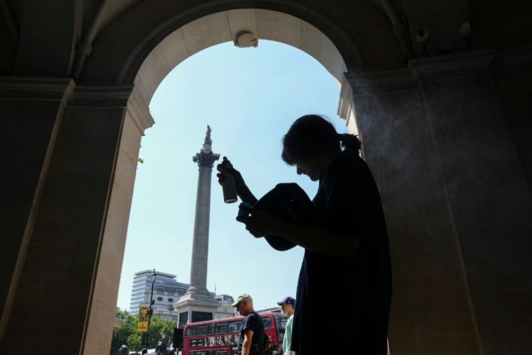 Une femme se protège de la chaleur du soleil, dans l'ombre d'une entrée sur Trafalgar Square, à Londres, le 8 juillet 2026 ( AFP / CARLOS JASSO )