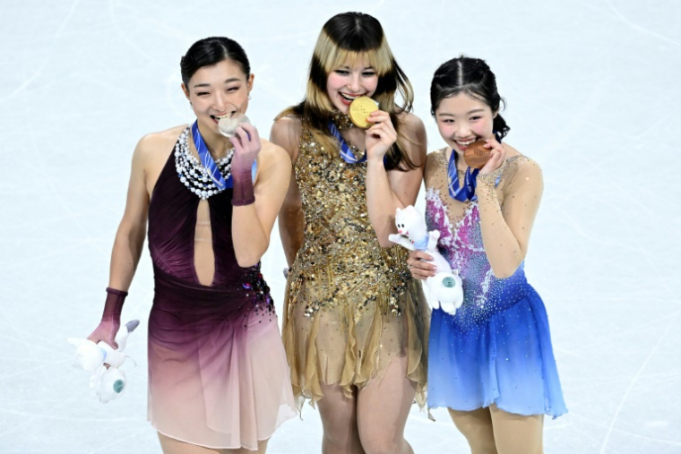 La championne olympique, l'Américaine Alysa Liu, entourée des Japonaises Kaori Sakamoto (g) et Ami Nakai, le 19 février 2026 à Milan ( AFP / WANG Zhao )