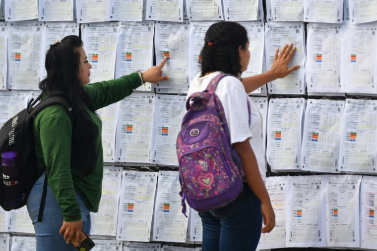 Deux femmes regardent le "mur de la victoire" à l'extérieur du centre logistique électoral, où a lieu le recomptage des voix de l'élection présidentielle du Honduras, à Tegucigalpa le 19 décembre 2025 ( AFP / Orlando SIERRA )