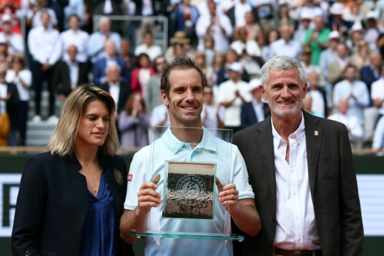 Entouré d'Amélie Mauresmo, directrice du tournoi, et de Gilles Moretton, président de la FFT, Richard Gasquet reçoit un trophée récompensant l'ensemble de sa carrière. ( AFP / ALAIN JOCARD )
