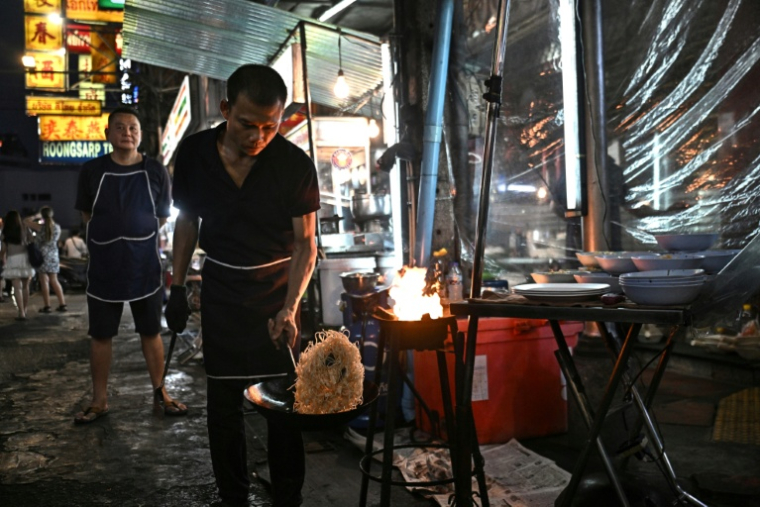 Un vendeur de rue prépare des nouilles sautées, le 29 avril 2026 à Bangkok  ( AFP / Lillian SUWANRUMPHA )