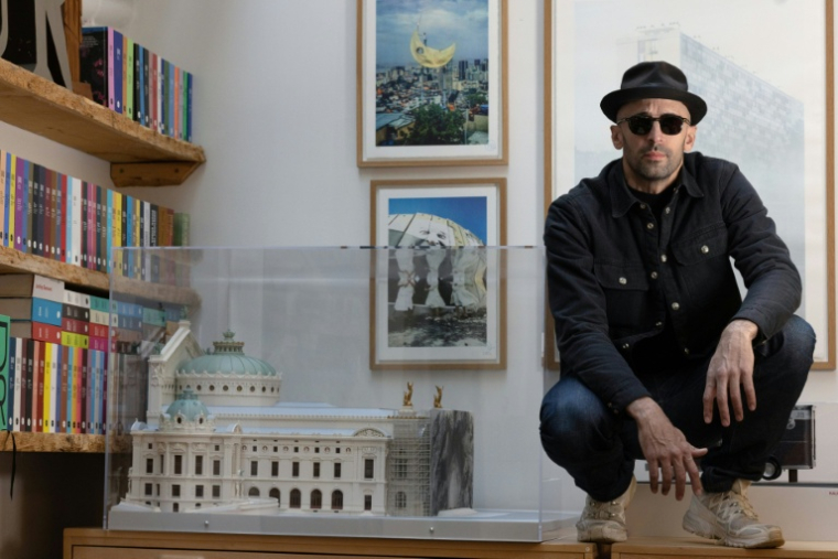 L'artiste JR dans son atelier parisien, le 26 novembre 2025, posant à côté d'une maquette de "caverne" sur la facade de l'Opéra Garnier en 2023  ( AFP / JOEL SAGET )