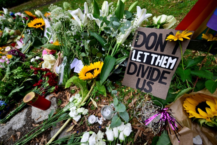 Des fleurs, des bougies et une pancarte avec "Ne les laissons pas nous diviser" ont été déposées en hommage aux victimes dans le parc Tiergarten à Berlin, le 27 juillet 2026 ( AFP / John MACDOUGALL )