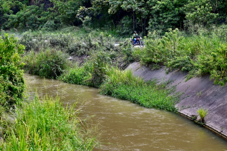 Une moto circule sur la route longeant ce que l'on appelle communément le "canal de la mort", dans le nord-ouest de Guayaquil, en Equateur, le 29 juin 2026. Des centaines de corps de victimes d'enlèvements, d'actes criminels ou d'affrontements entre gangs ont été retrouvés dans le "canal de la mort" ( AFP / MARCOS PIN )