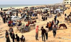 Des Palestiniens attendent l'arrivée de camions transportant des sacs de farine, près d'un point de contrôle israélien, dans la ville de Gaza