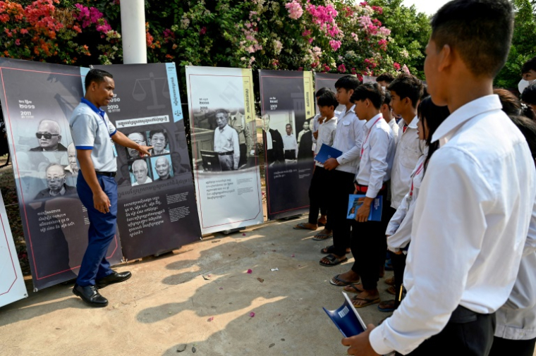 Des Cambodgiens circulant à bord d'un bus itinérant transformé en musée expliquent à des collégiens le génocide des Khmers rouges, lors d'un programme de sensibilisation dans le district de Phnomk Srok, de la province de Banteay Meanchey, le 24 mars 2025 ( AFP / TANG CHHIN Sothy )