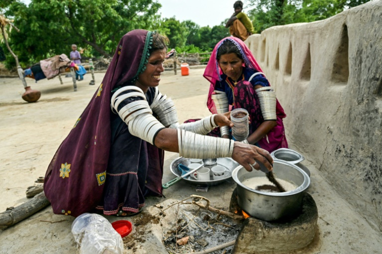 Jamna Kolhi (g) et sa parente Reshma, portant des tatouages et des tenues indigènes, préparent du thé au village de Ponjo Kolhi, à environ 30 km d'Umerkot, un district à majorité hindoue, le 14 juillet 2025 au Pakistan ( AFP / Asif HASSAN )