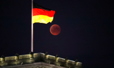La lune est visible à côté du drapeau allemand au sommet du bâtiment du Reichstag
