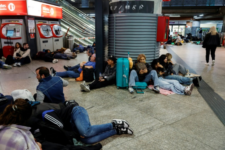 Des voyageurs se préparant à passer la nuit à la gare d'Atocha, à Madrid, à cause de la panne d'électricté géante, le 28 avril 2025 ( AFP / Óscar del Pozo )